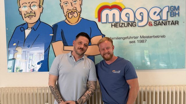 Thomas Mager (Helmut Mager GmbH) und Kevin Stumpf (DreiHundertSechzig) vor dem Mager-Logo im Büro in Düren